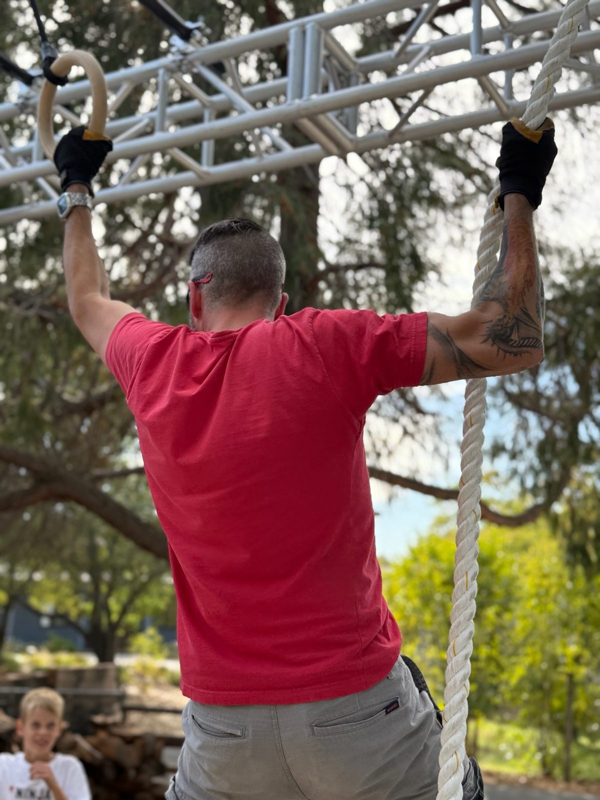 An adult athlete training on the rings at a Lightning Ninja Academy course