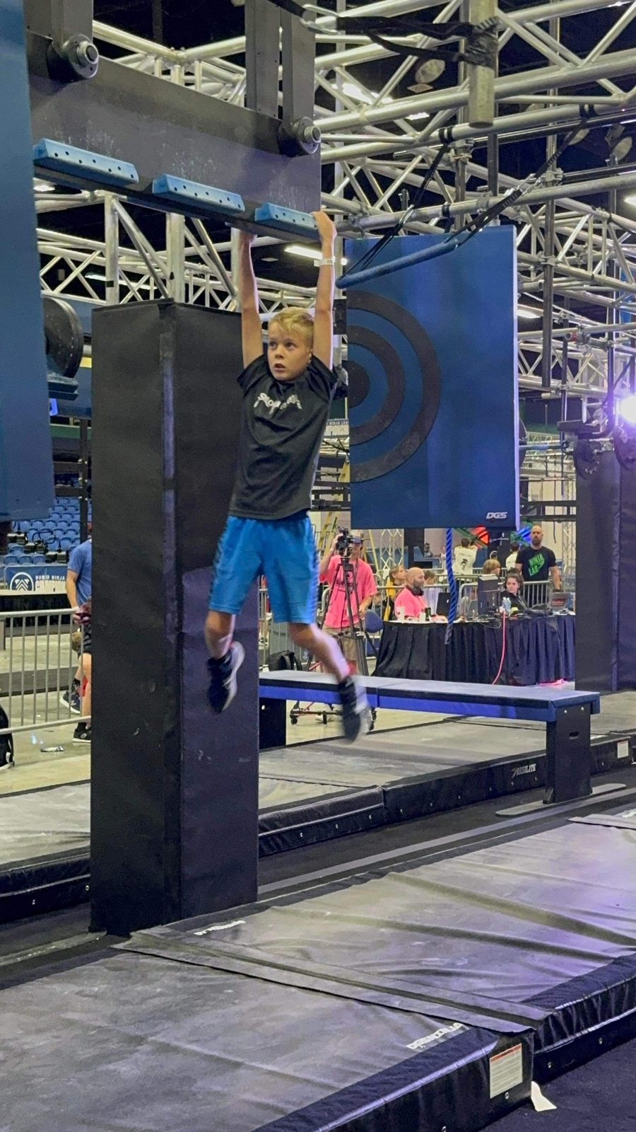 A young ninja swinging across hanging obstacles